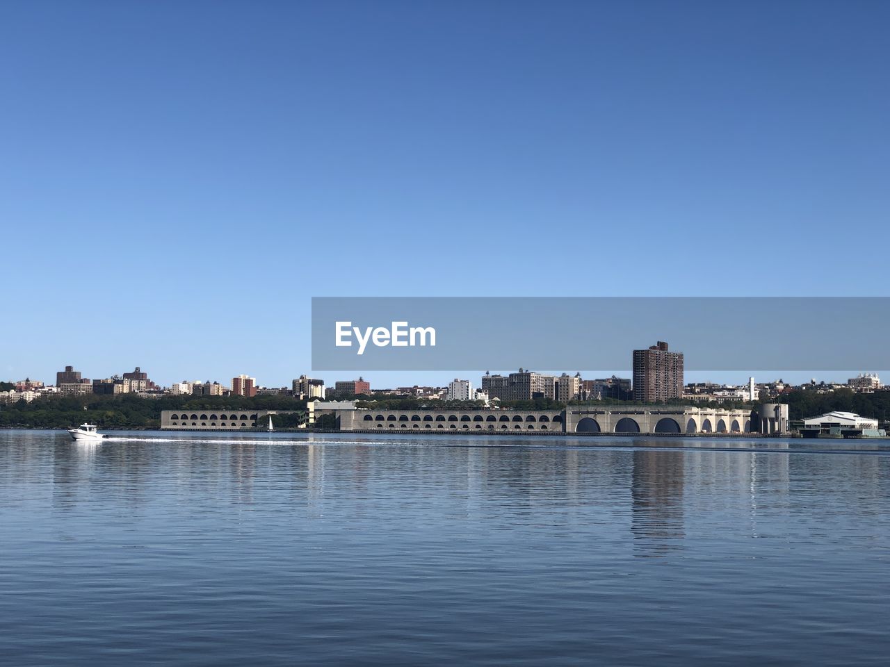 River by buildings against clear blue sky