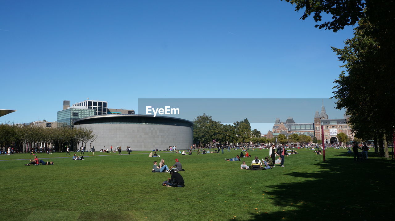 PEOPLE AT PARK AGAINST BLUE SKY