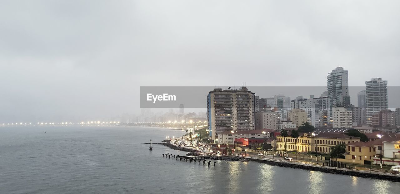 SEA BY BUILDINGS IN CITY AGAINST SKY