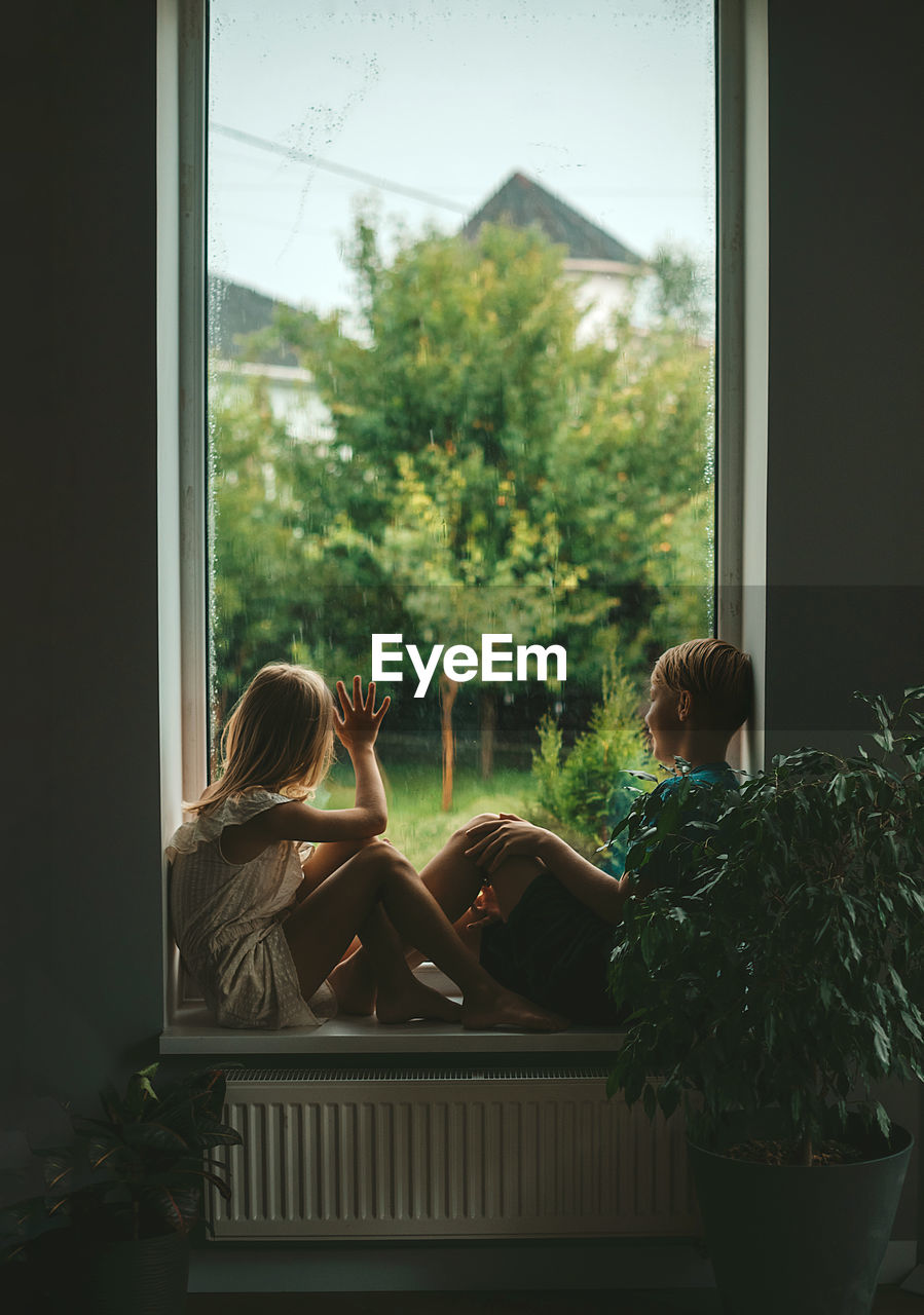 Rear view of kids  looking through window