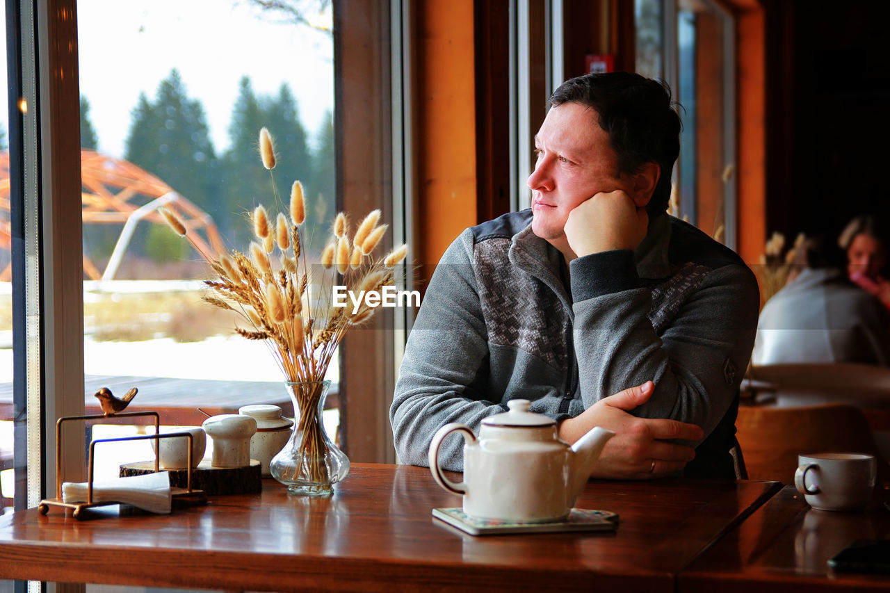 Man looking away while sitting at restaurant