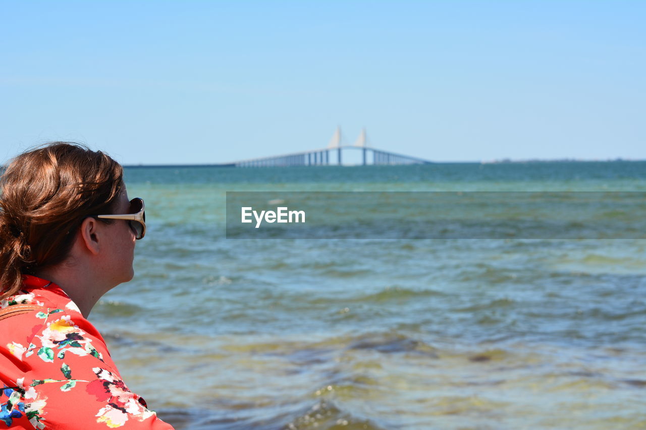 Side view of woman against sunshine skyway bridge over tampa bay