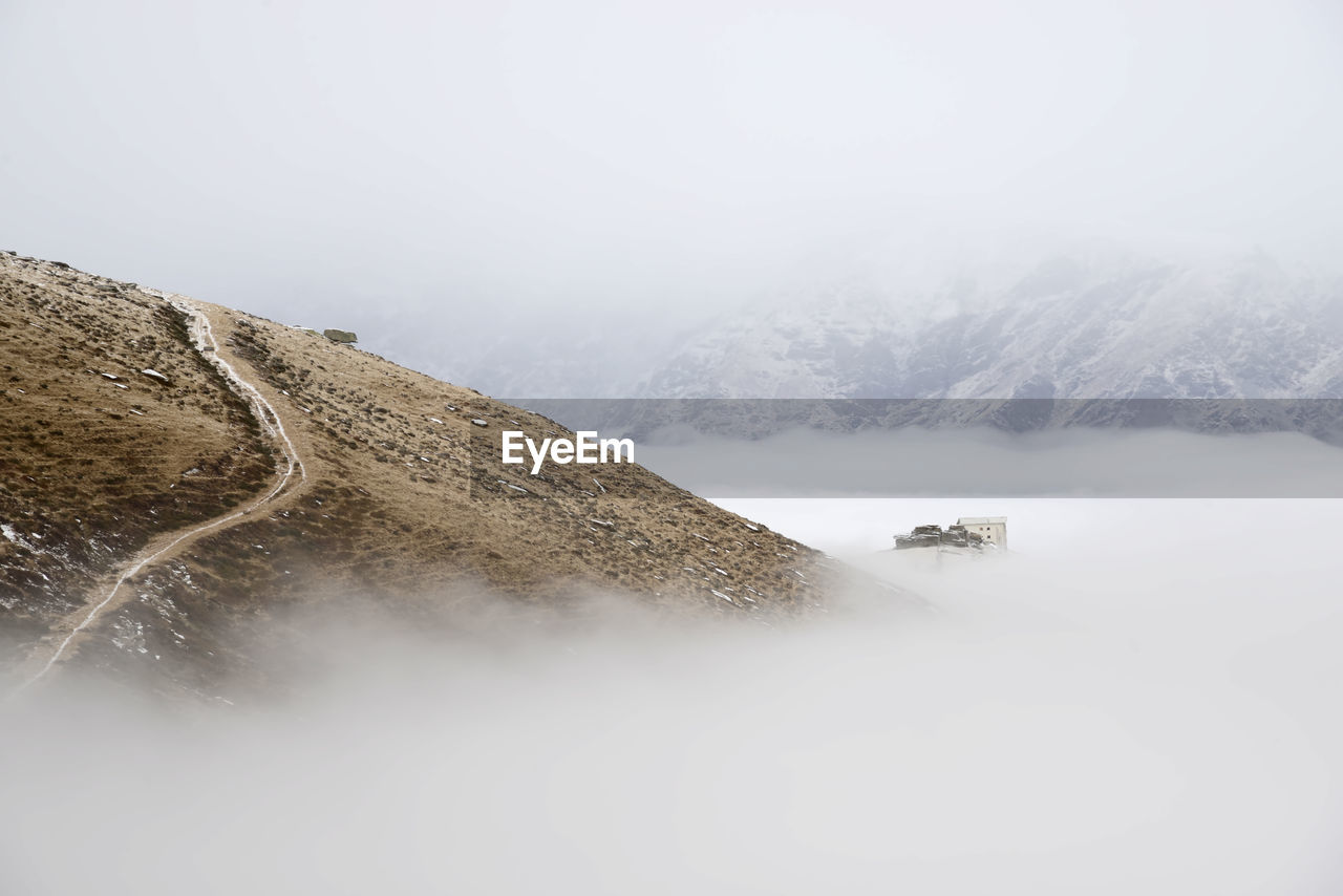 Scenic view of sea of clouds and an house as island against sky