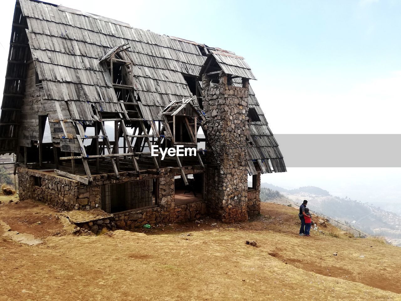 Father and daughter by old abandoned building against sky