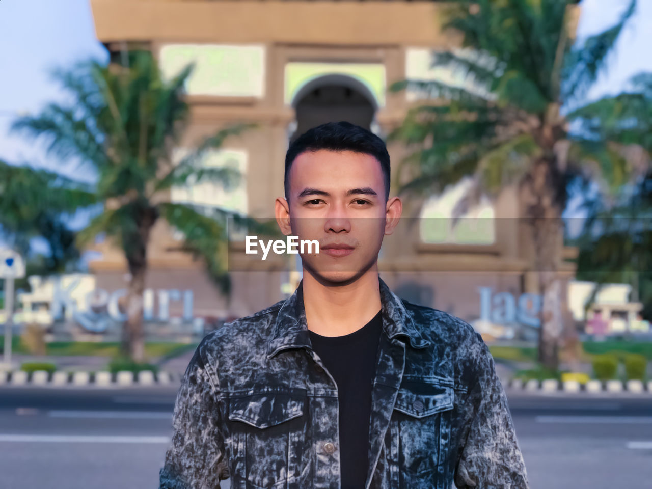 Portrait of young man standing on street in city