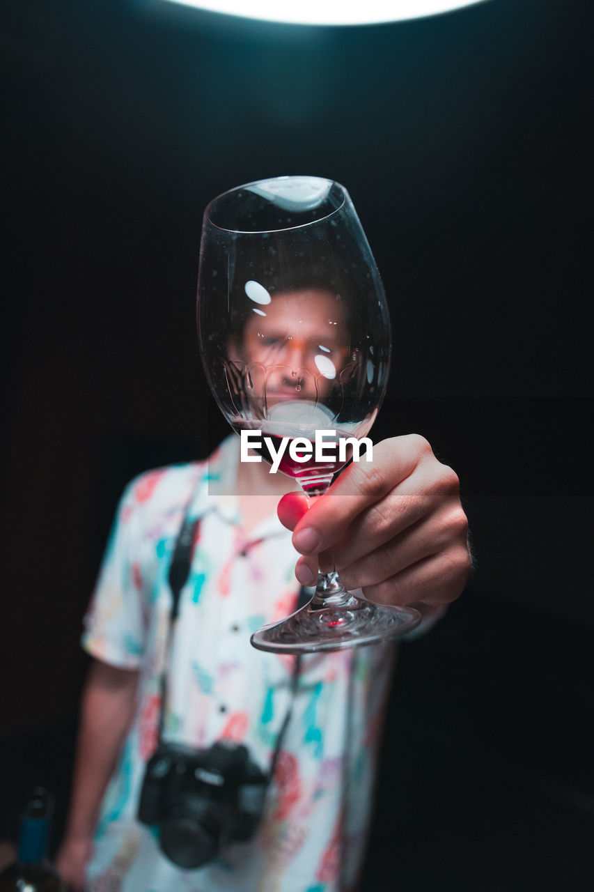 Man holding wineglass against black background