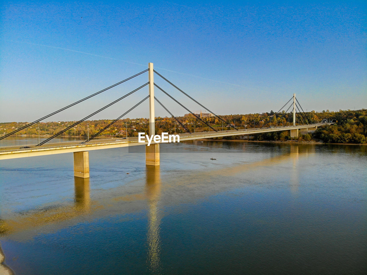 Suspension bridge over river against clear blue sky