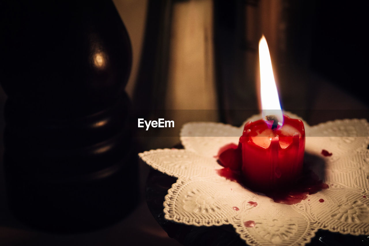 Lit candle on table in darkroom