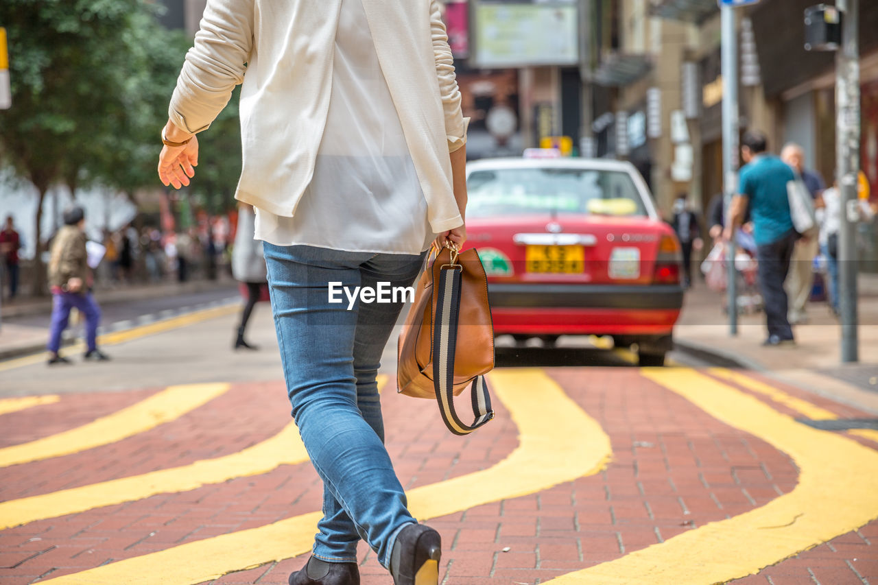 Low section of woman walking on city street