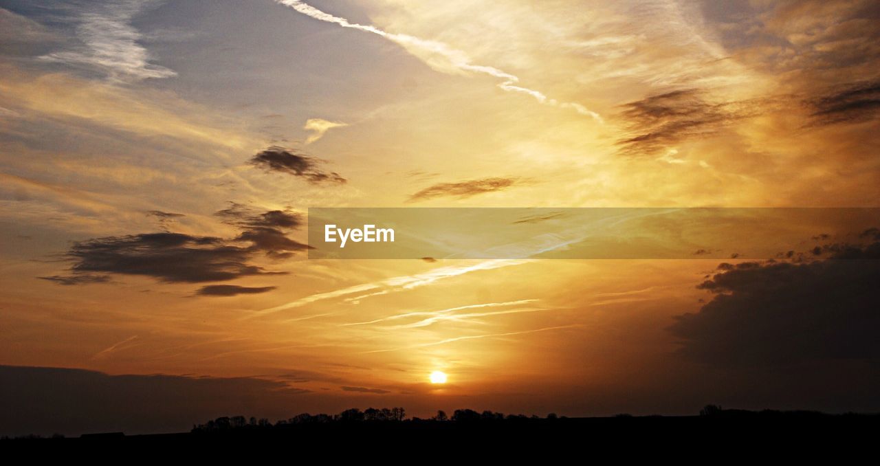 Scenic view of sunset over silhouette field