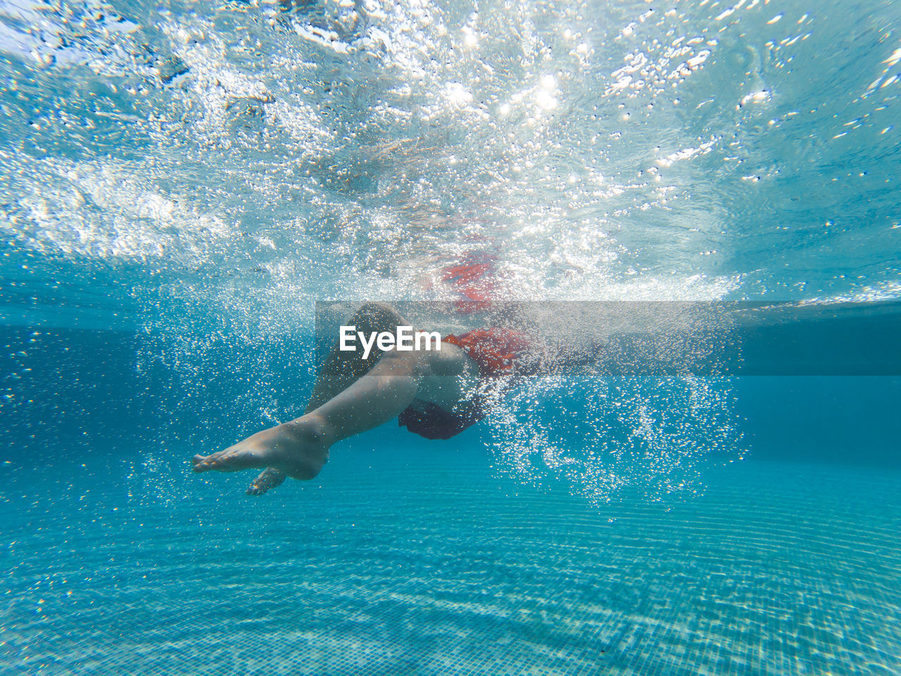 Girl swimming underwater in swimming pool