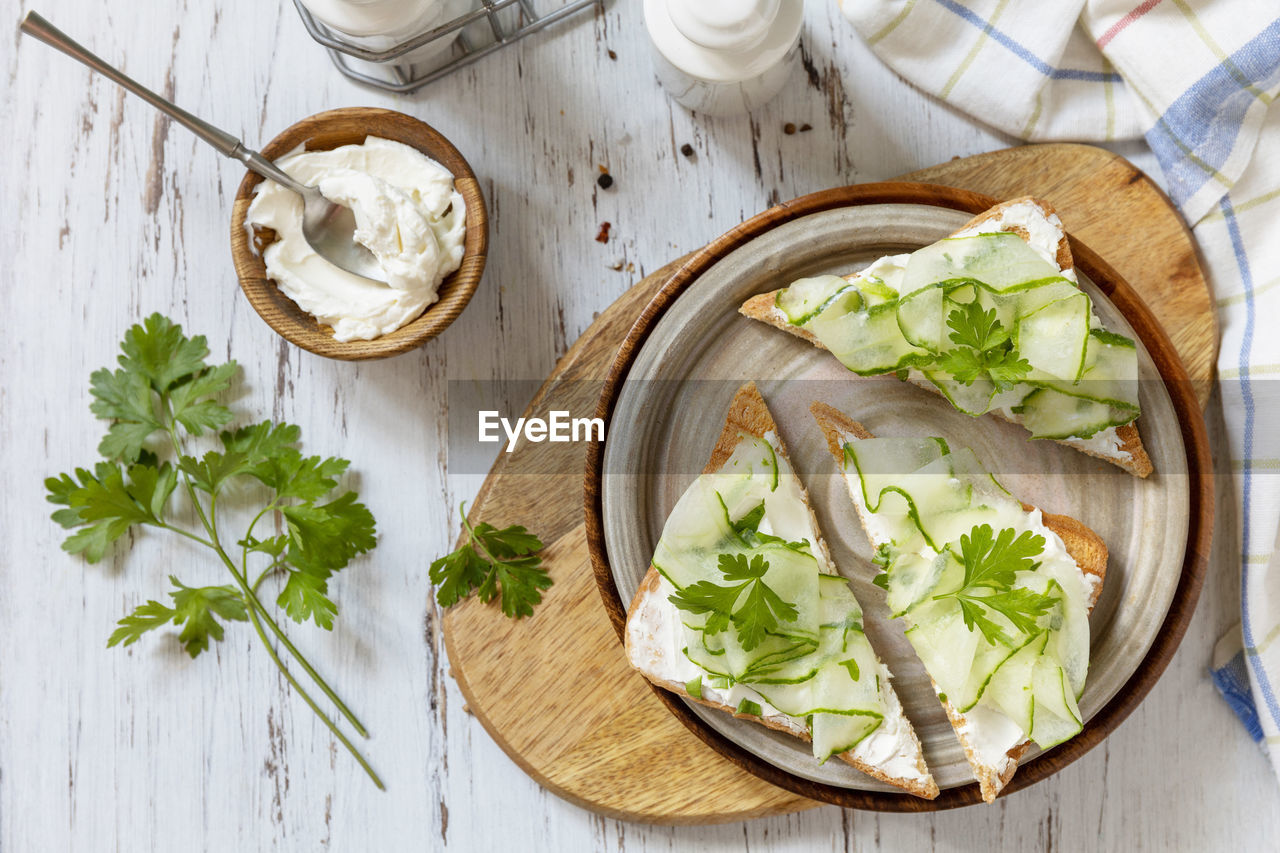 Healthy breakfast or holiday snacks. toast with cucumbers, herbs and ricotta on a rustic table. 