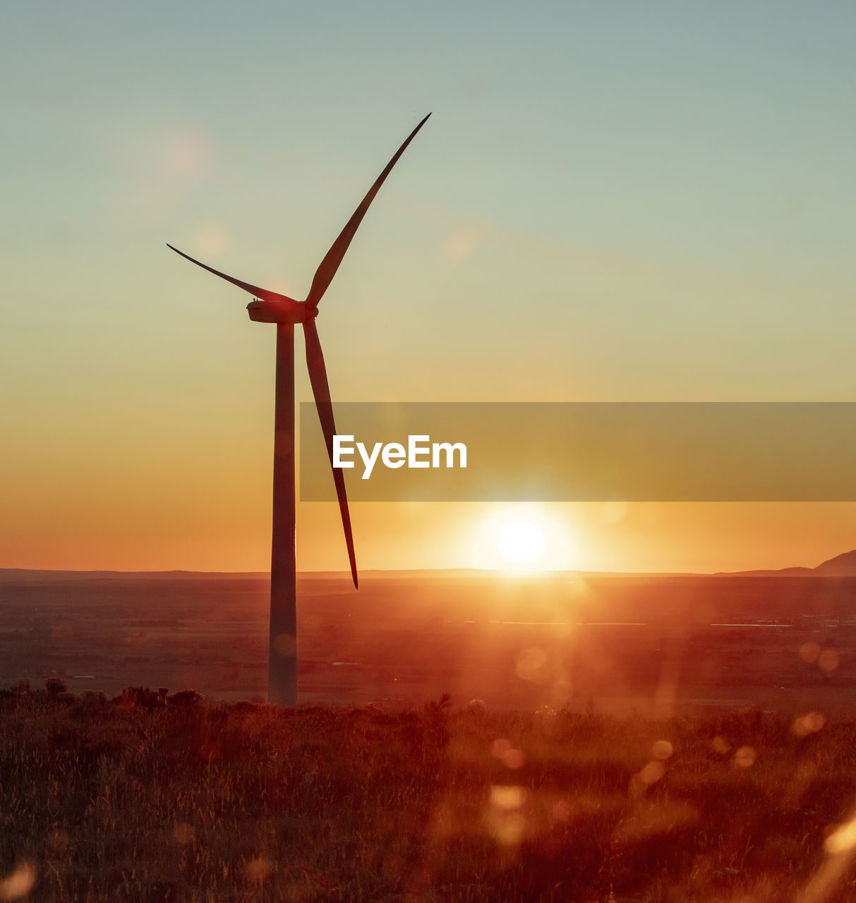 Wind turbines on field during sunset