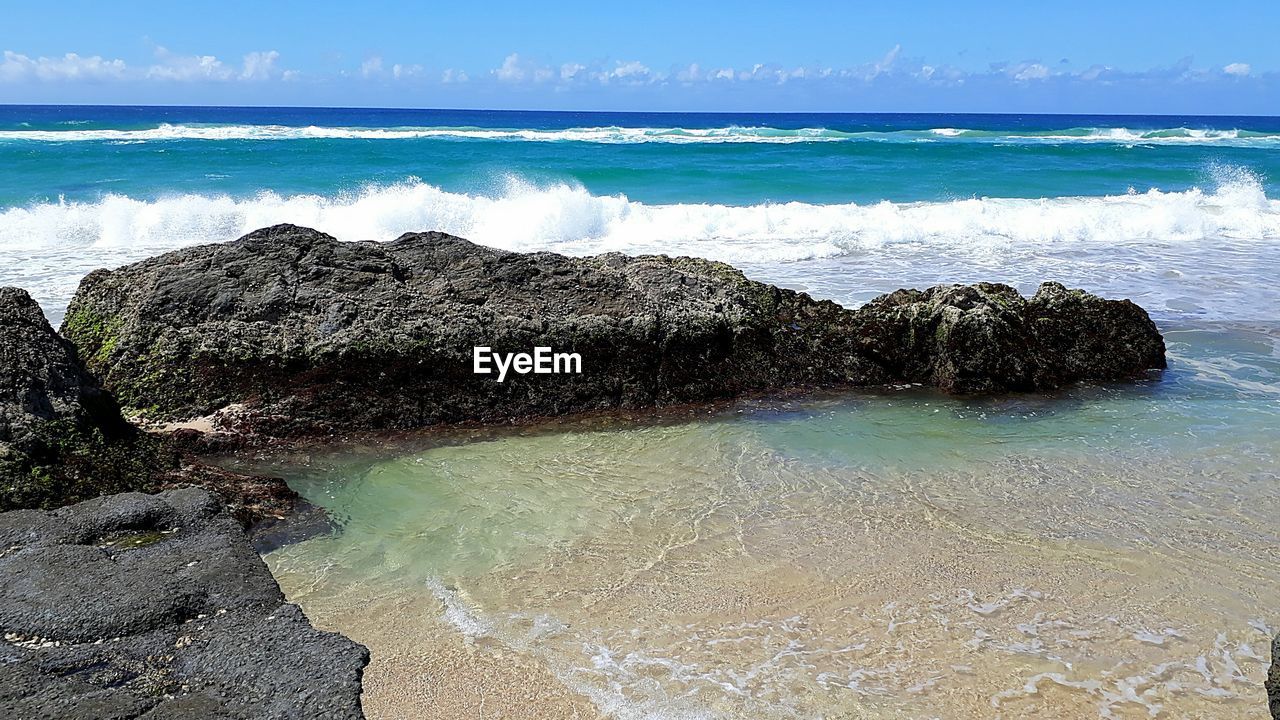 SCENIC VIEW OF ROCKS ON SHORE AGAINST SKY