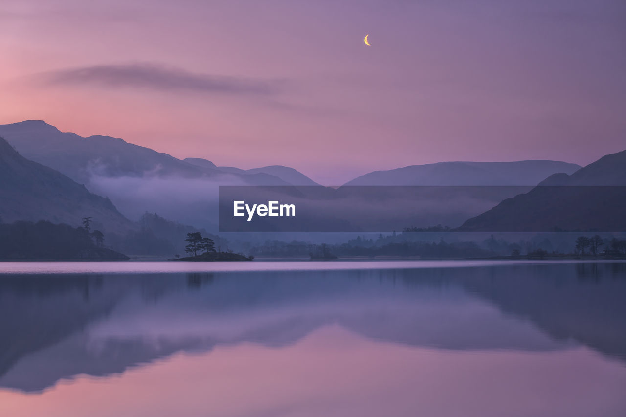 Scenic view of lake against mountains during sunset