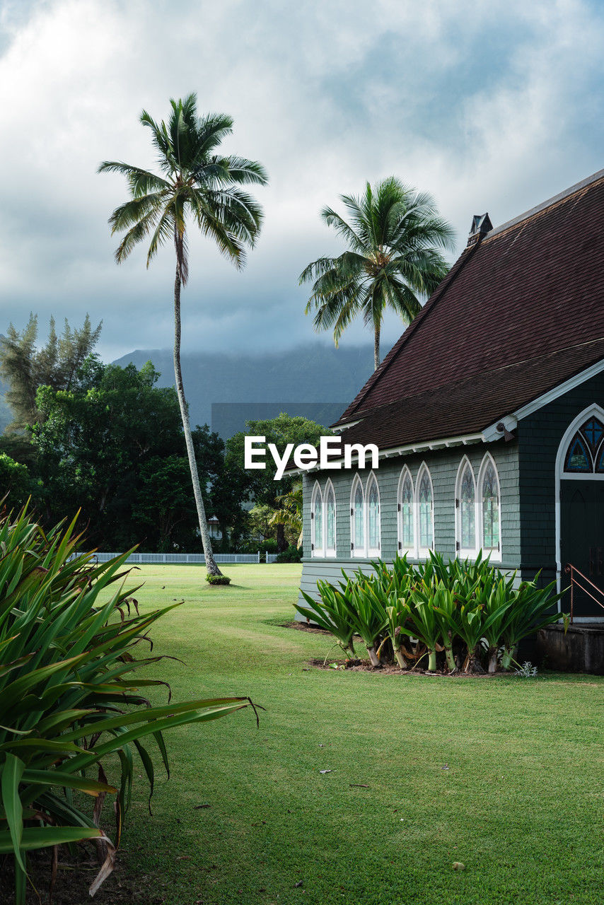 Scenic view of typical tropical building against palm tree and moody sky