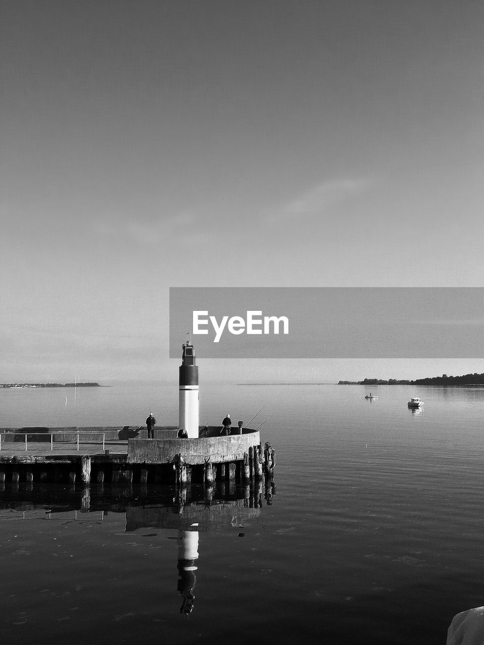 Lighthouse on pier over lake against sky