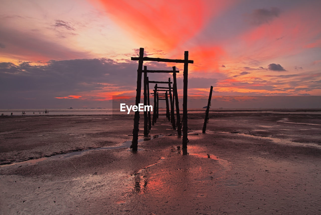 Built structure on beach against sky during sunset