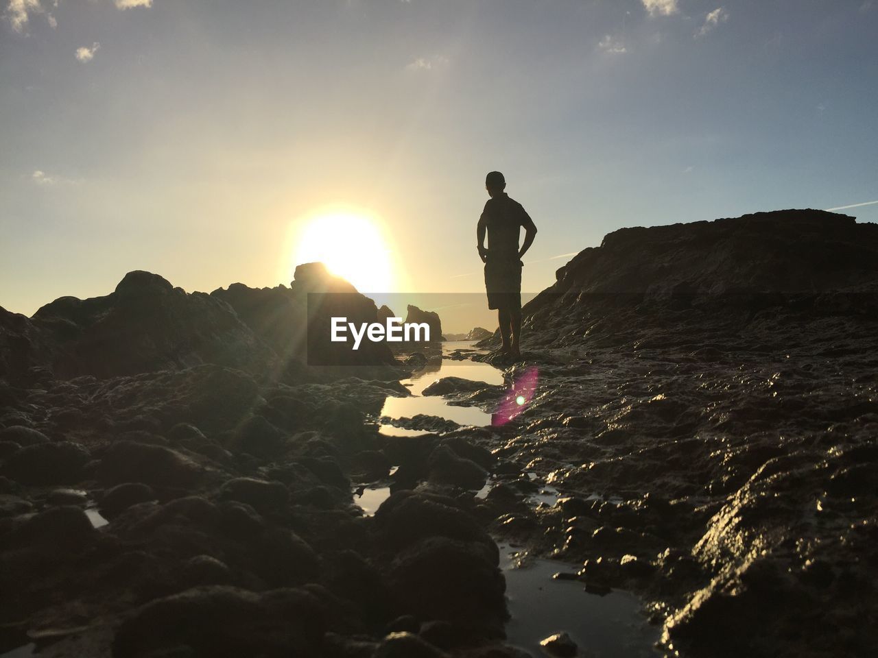 Man standing by sea against sky during sunset