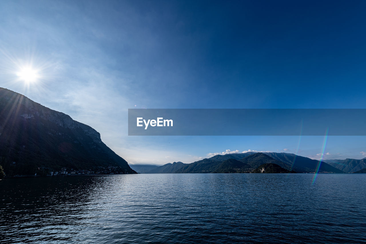 Scenic view of sea and mountains against blue sky