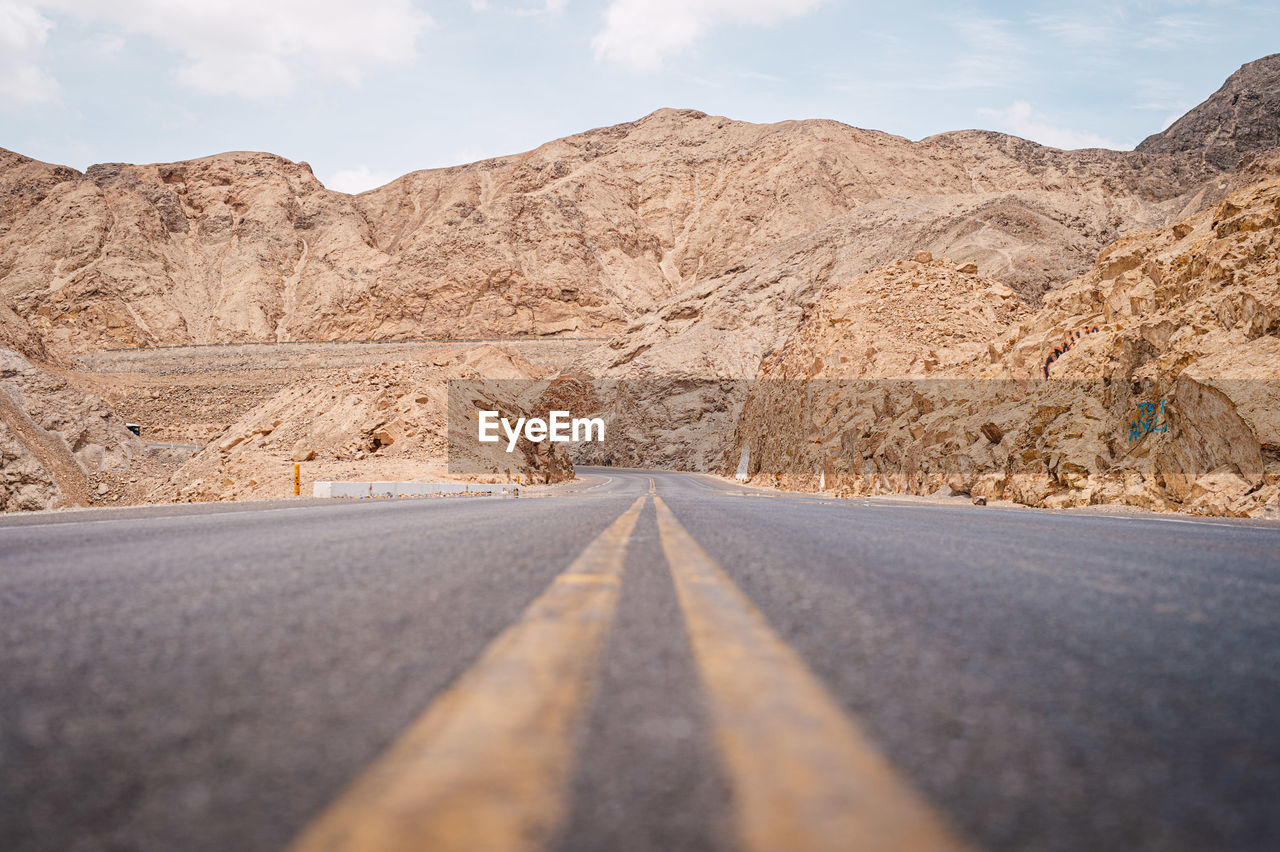 Surface level of empty road against mountain range and sky