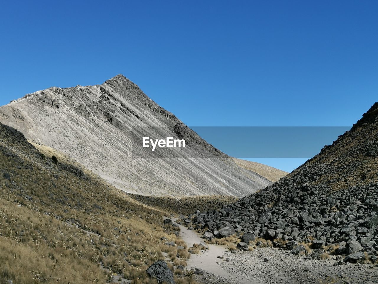 PANORAMIC VIEW OF MOUNTAIN RANGE AGAINST CLEAR BLUE SKY