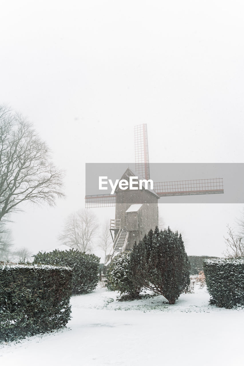 SNOW COVERED FIELD BY BUILDING AGAINST CLEAR SKY