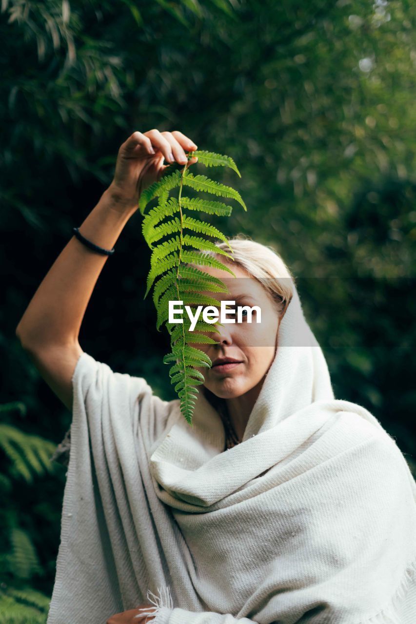 Cropped hand of woman standing against trees