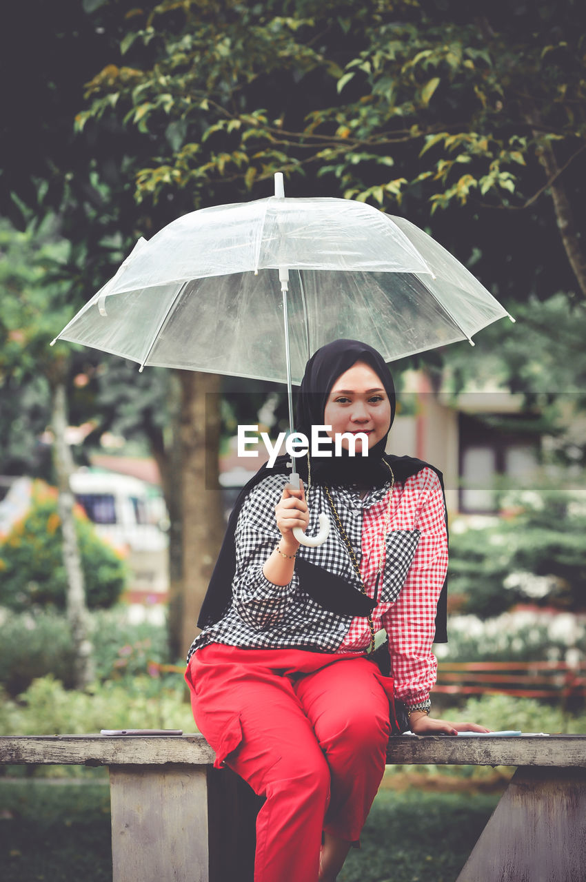 Portrait of woman with umbrella standing in rain during rainy season