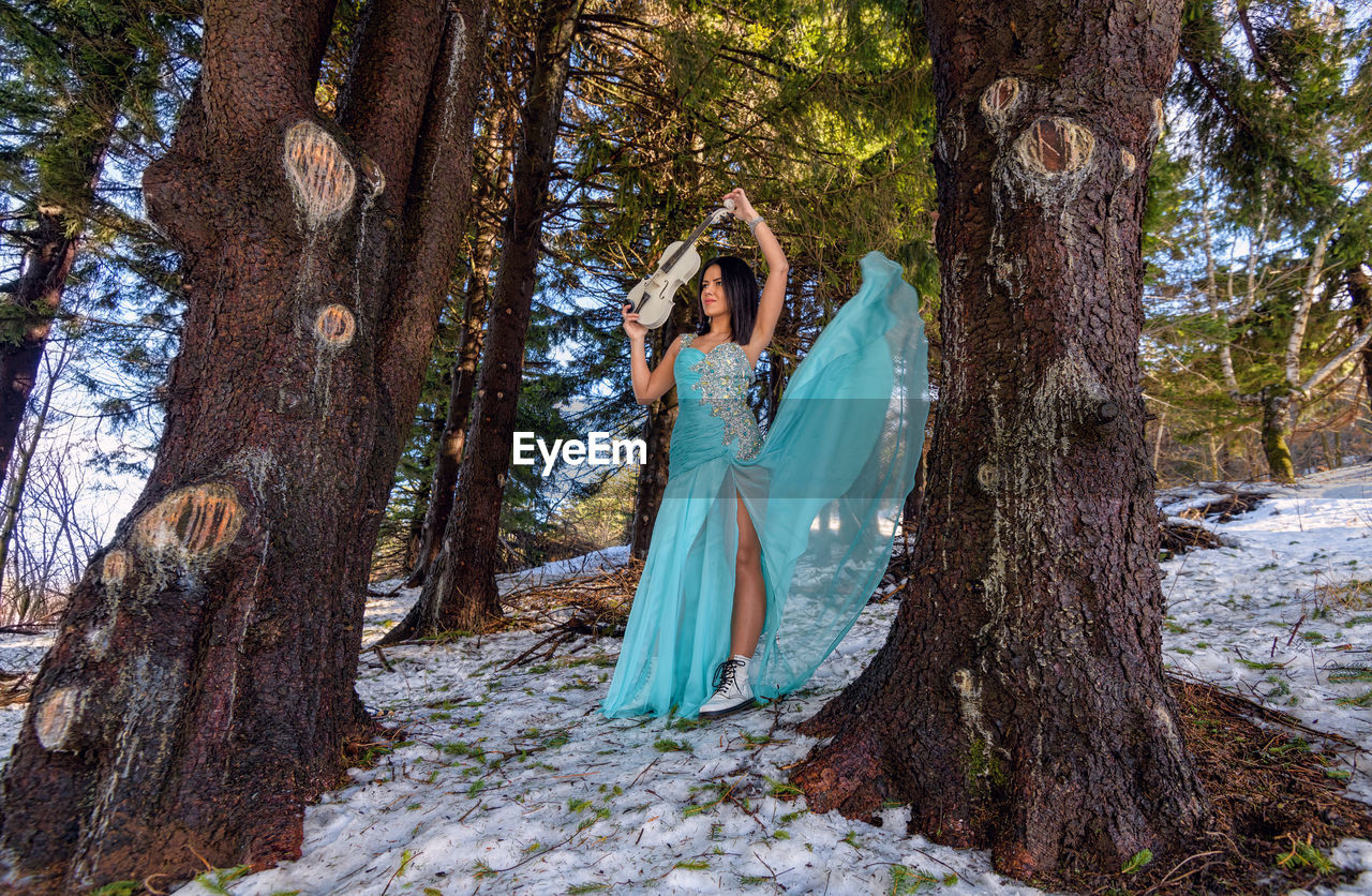 Woman playing on violin in the forest