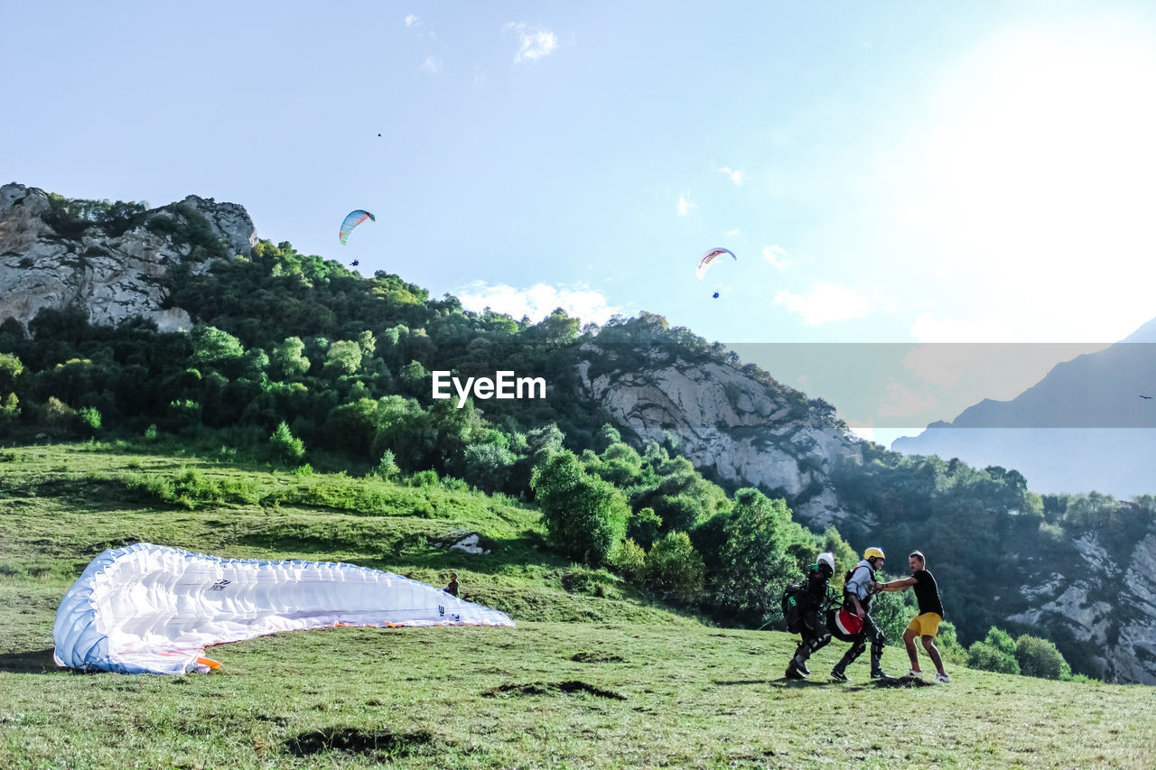 People paragliding on mountain peak against sky