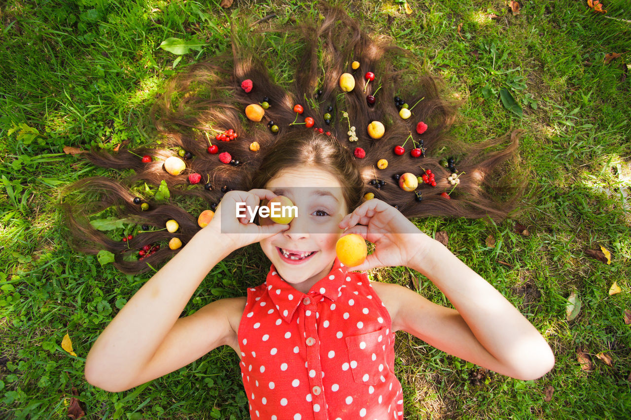 HIGH ANGLE VIEW OF GIRL MAKING FACE GROWING IN FIELD