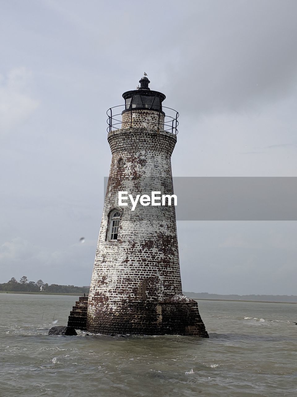 Lighthouse by sea against sky