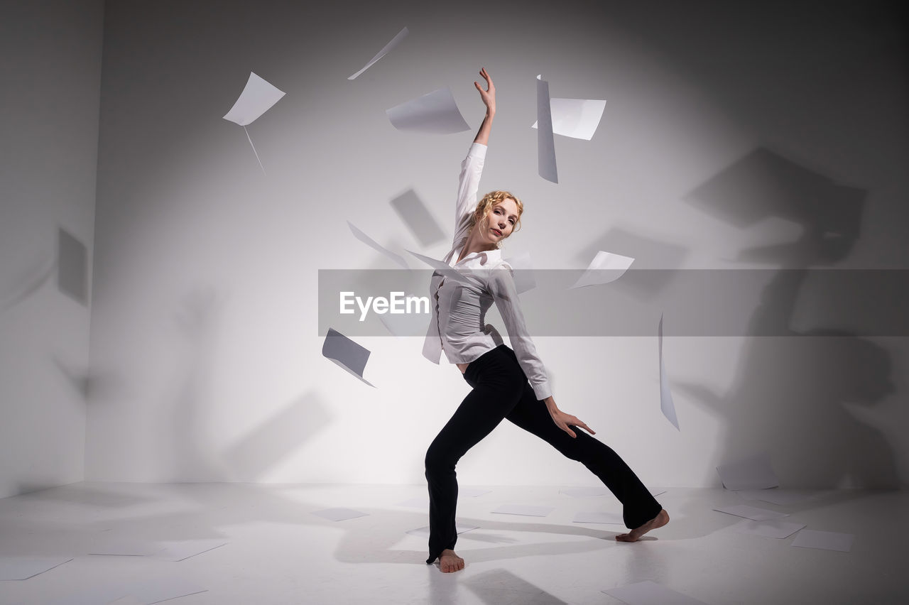 Full length of woman standing against white wall