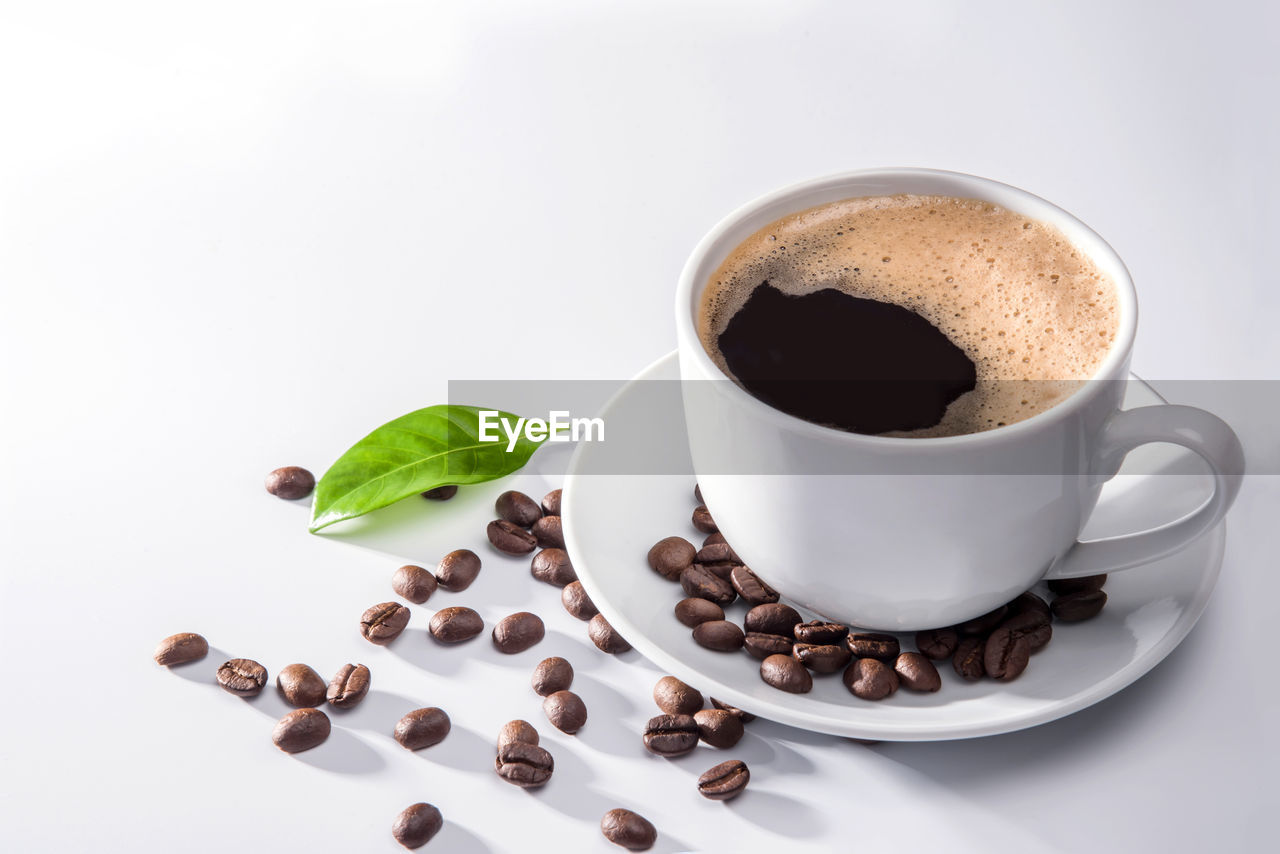 CLOSE-UP OF COFFEE CUP WITH SPOON AND WHITE BACKGROUND