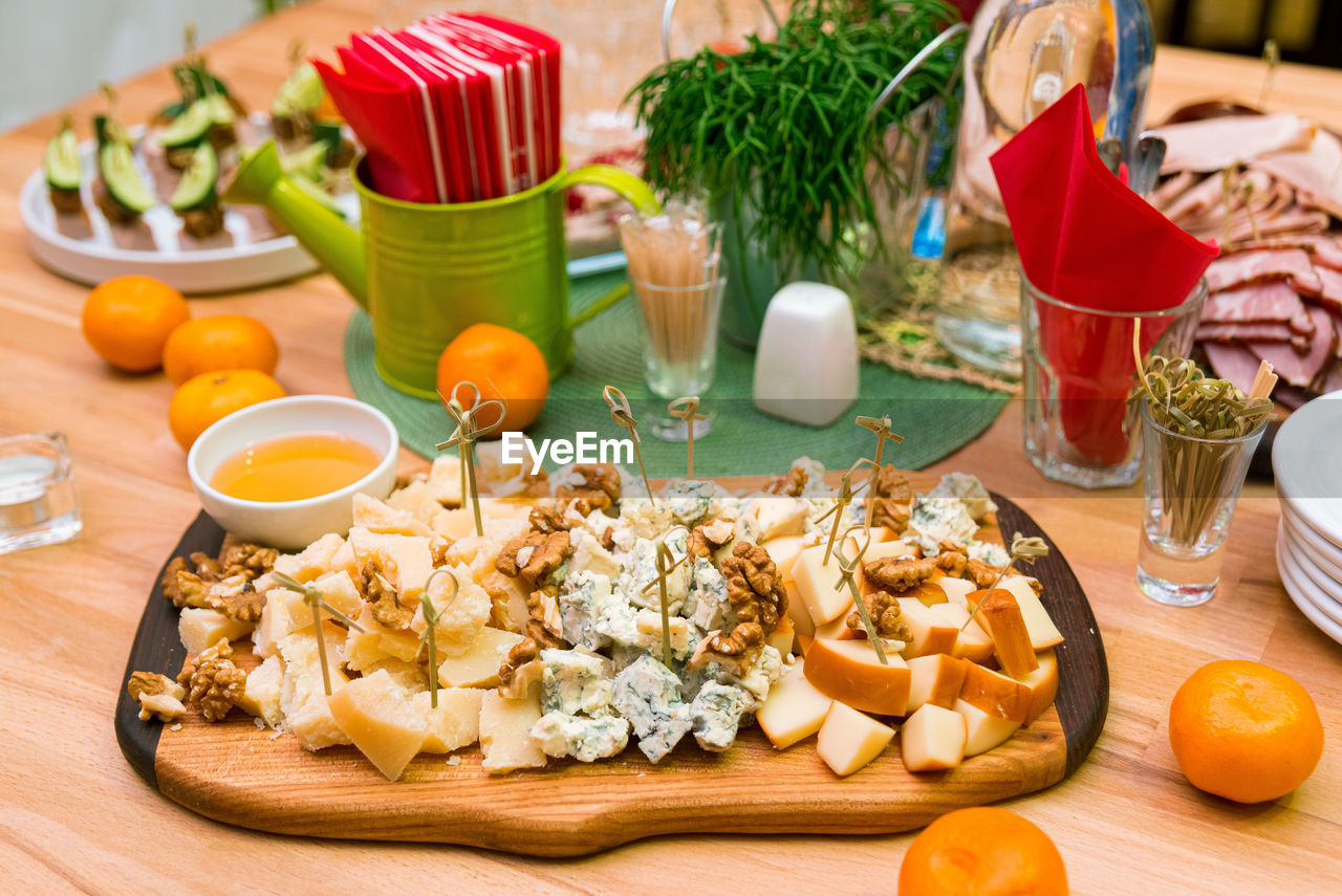 Wooden board with pieces of cheese, honey, walnuts. mold cheese gorgonzola, parmesan, smoked cheese