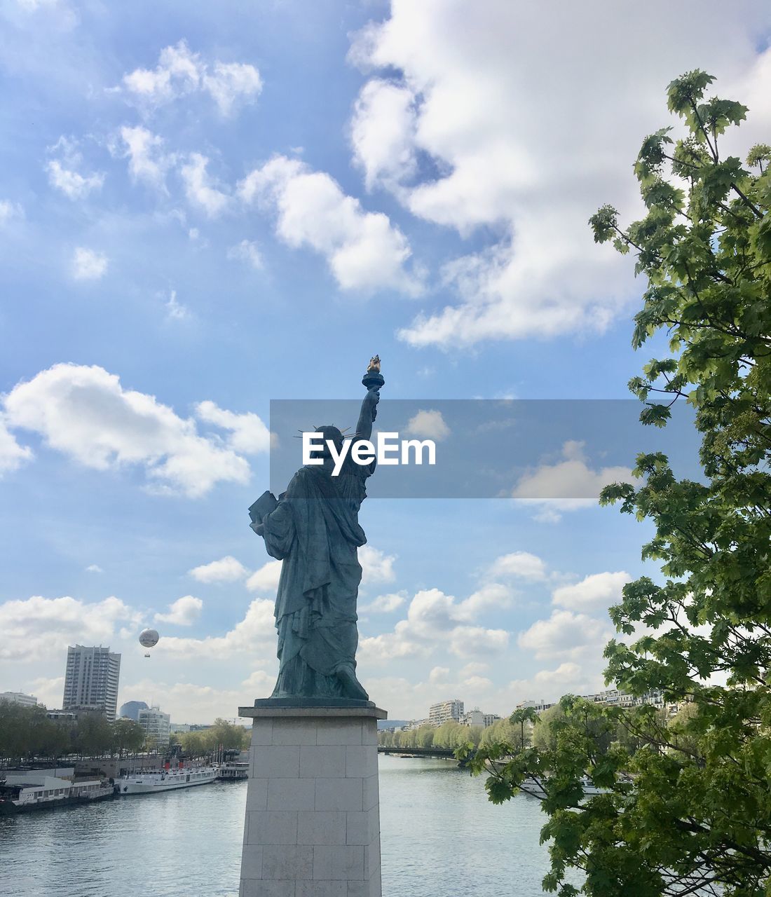 Rear view of statue of liberty over seine river against sky in paris 