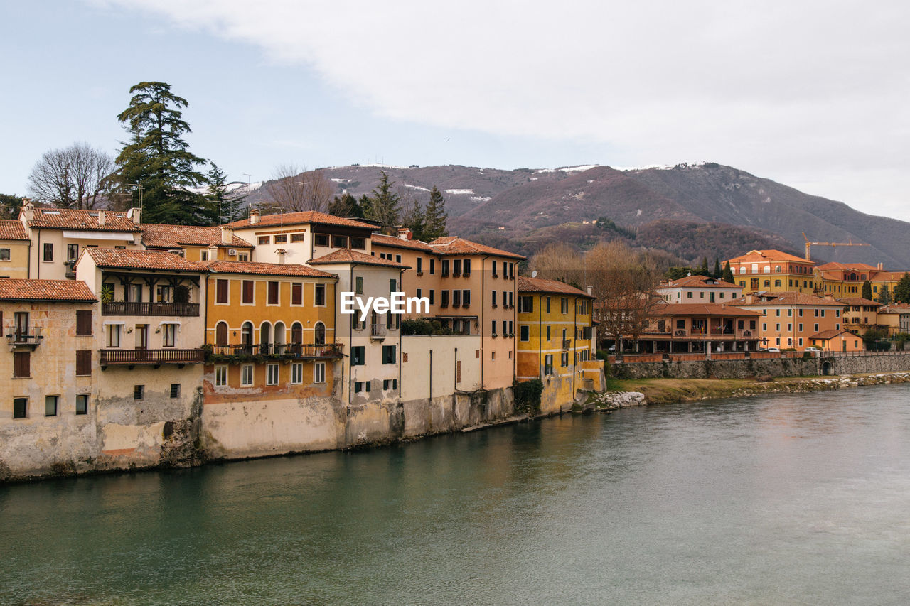 Residential buildings by river against sky