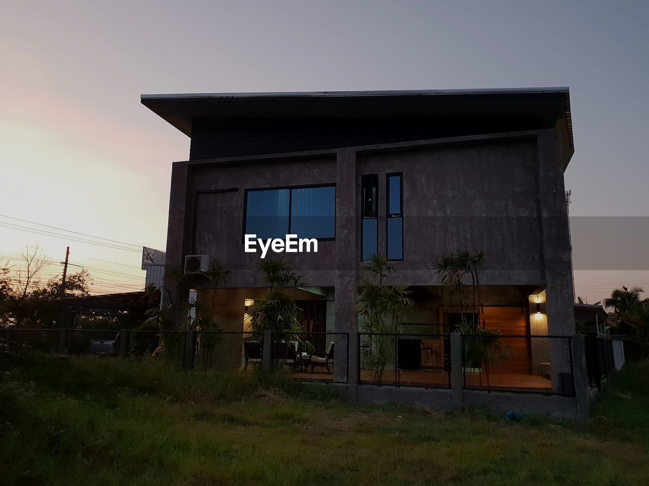 EXTERIOR OF HOUSE ON FIELD AGAINST SKY AT DUSK