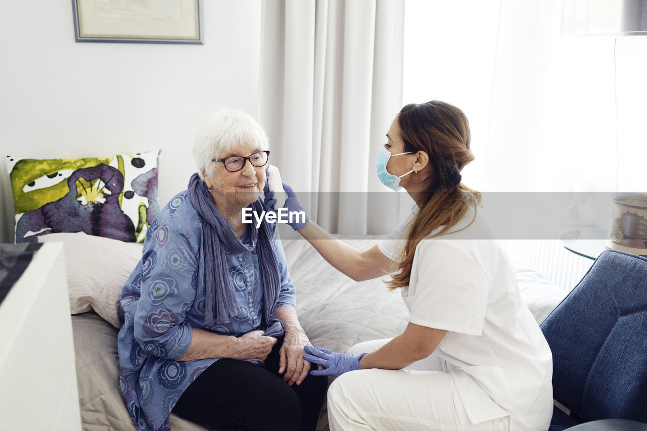 Nurse checking woman's temperature at home