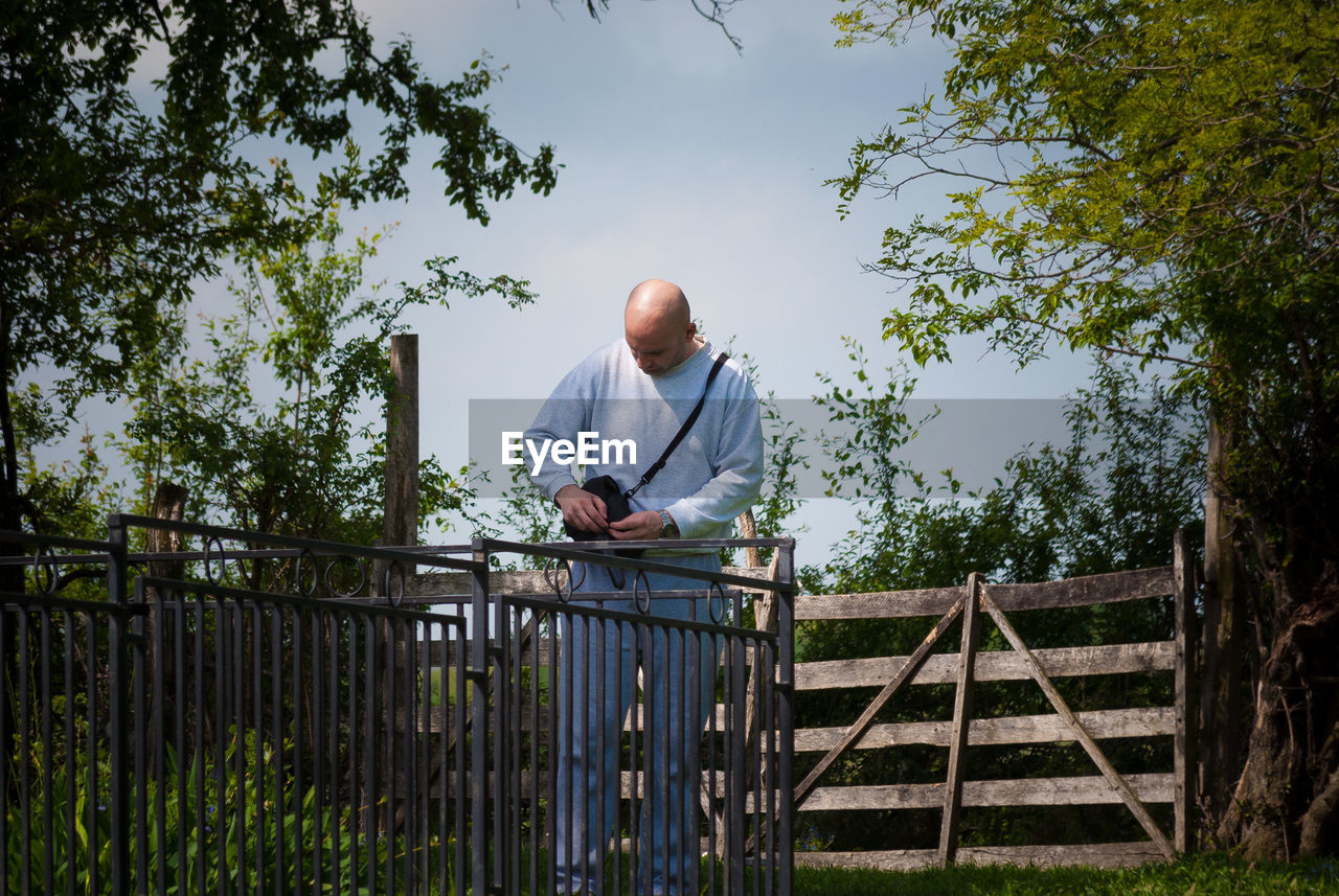 Low angle view of man standing by tree against sky