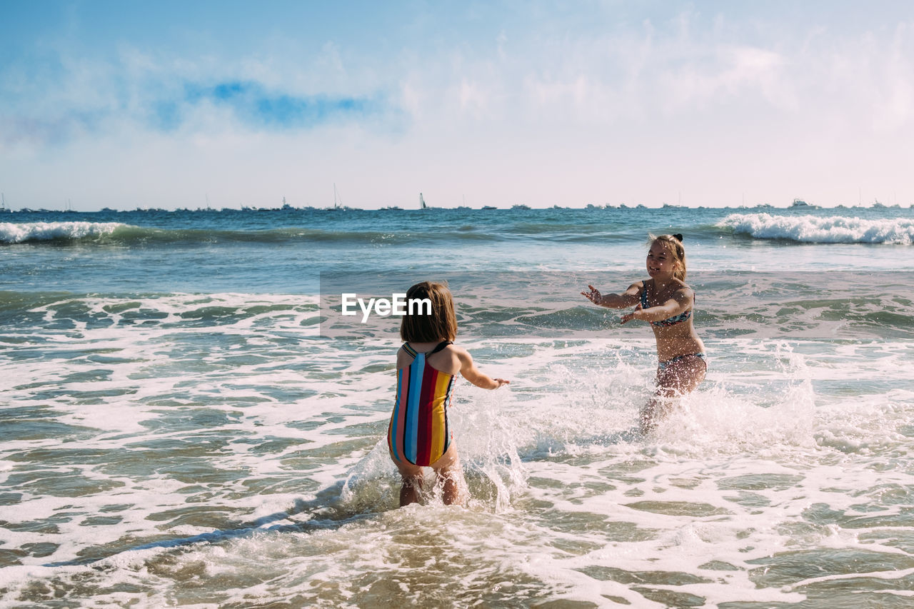 Sisters playing and splashing in the pacific ocean