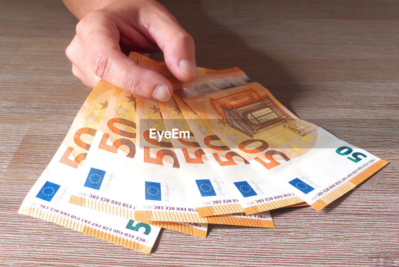 Cropped hand holding paper currency on table