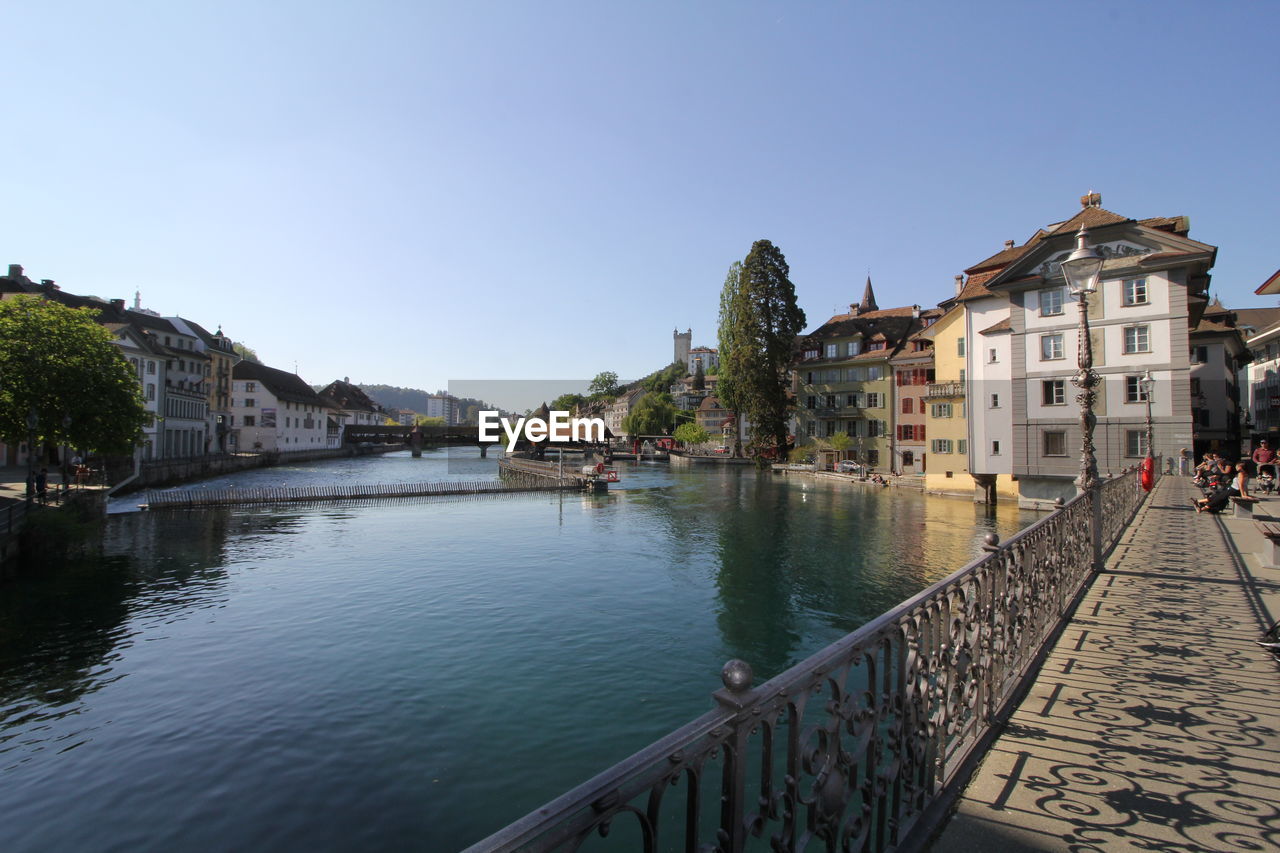 Bridge over river by buildings in city against sky