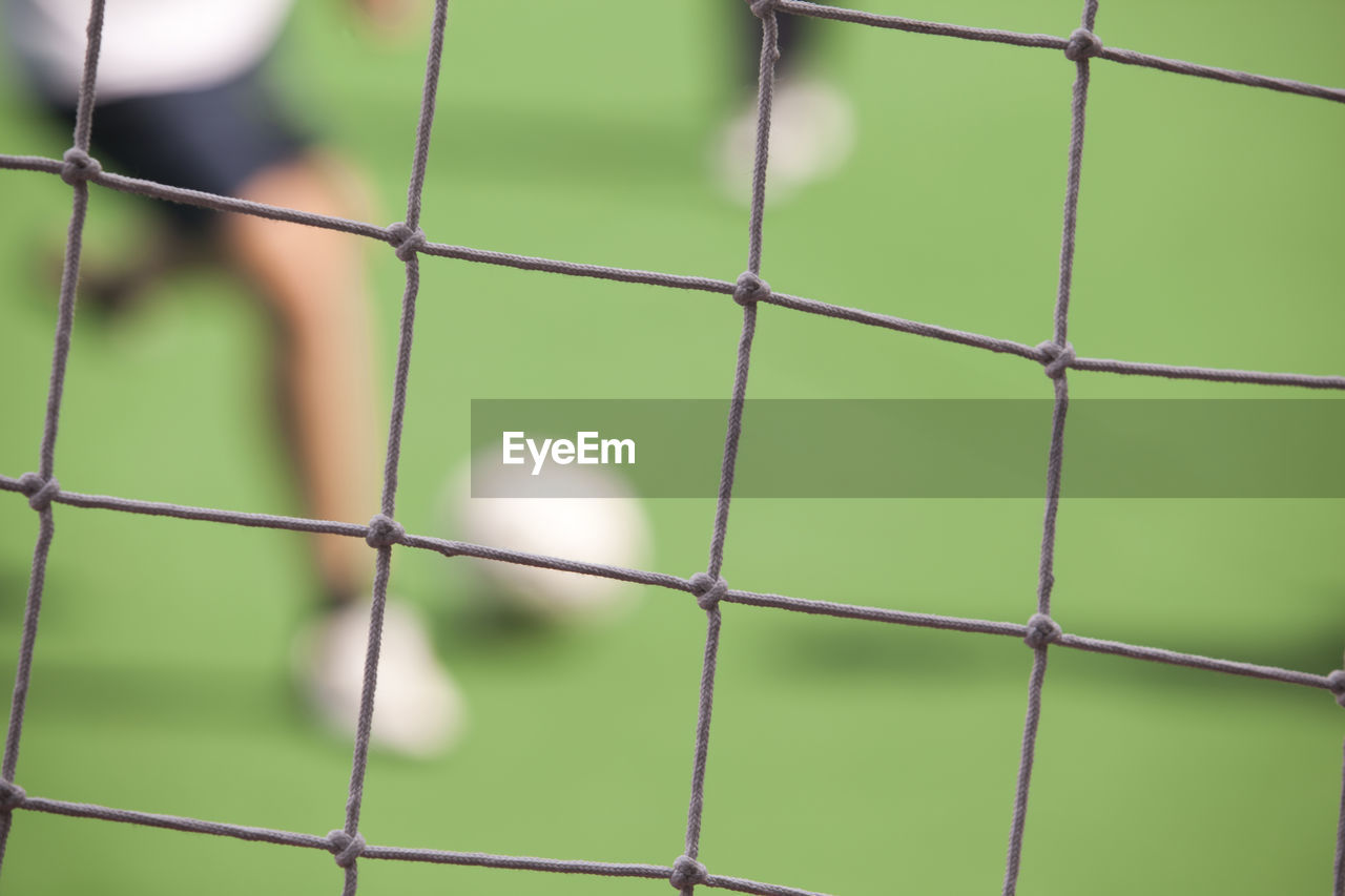 Full frame shot of net against players on soccer field