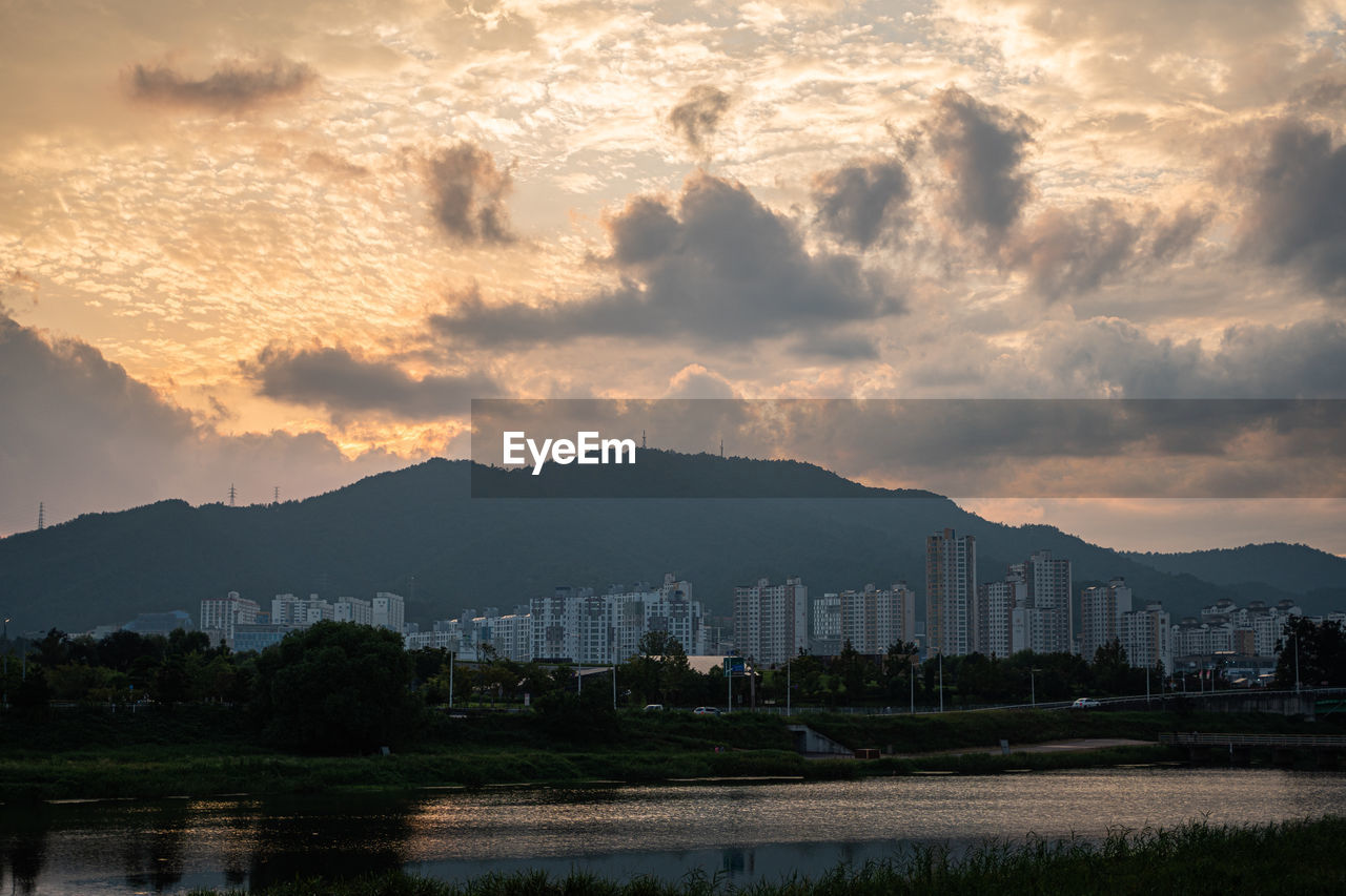 Scenic view of city by mountains against sky during sunset