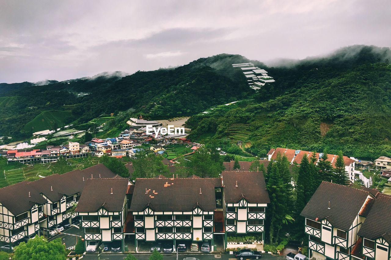 HIGH ANGLE VIEW OF HOUSES AND TREES AGAINST SKY