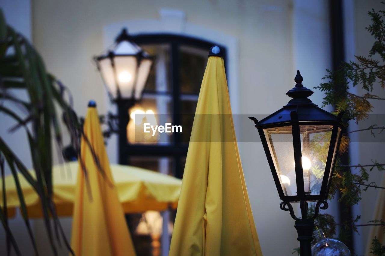 Close-up of parasols and illuminated lamp post at night