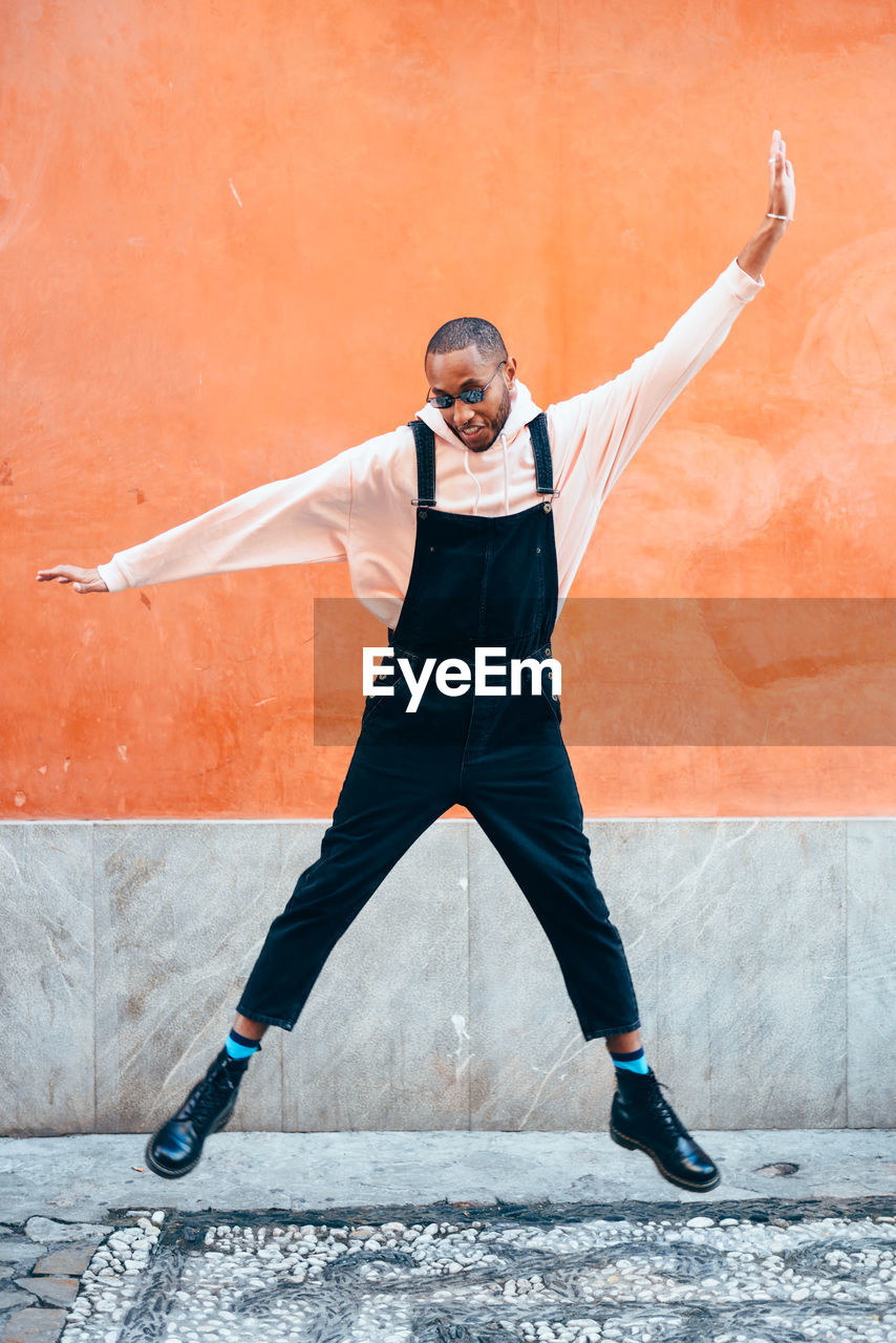 Full length of man jumping against wall