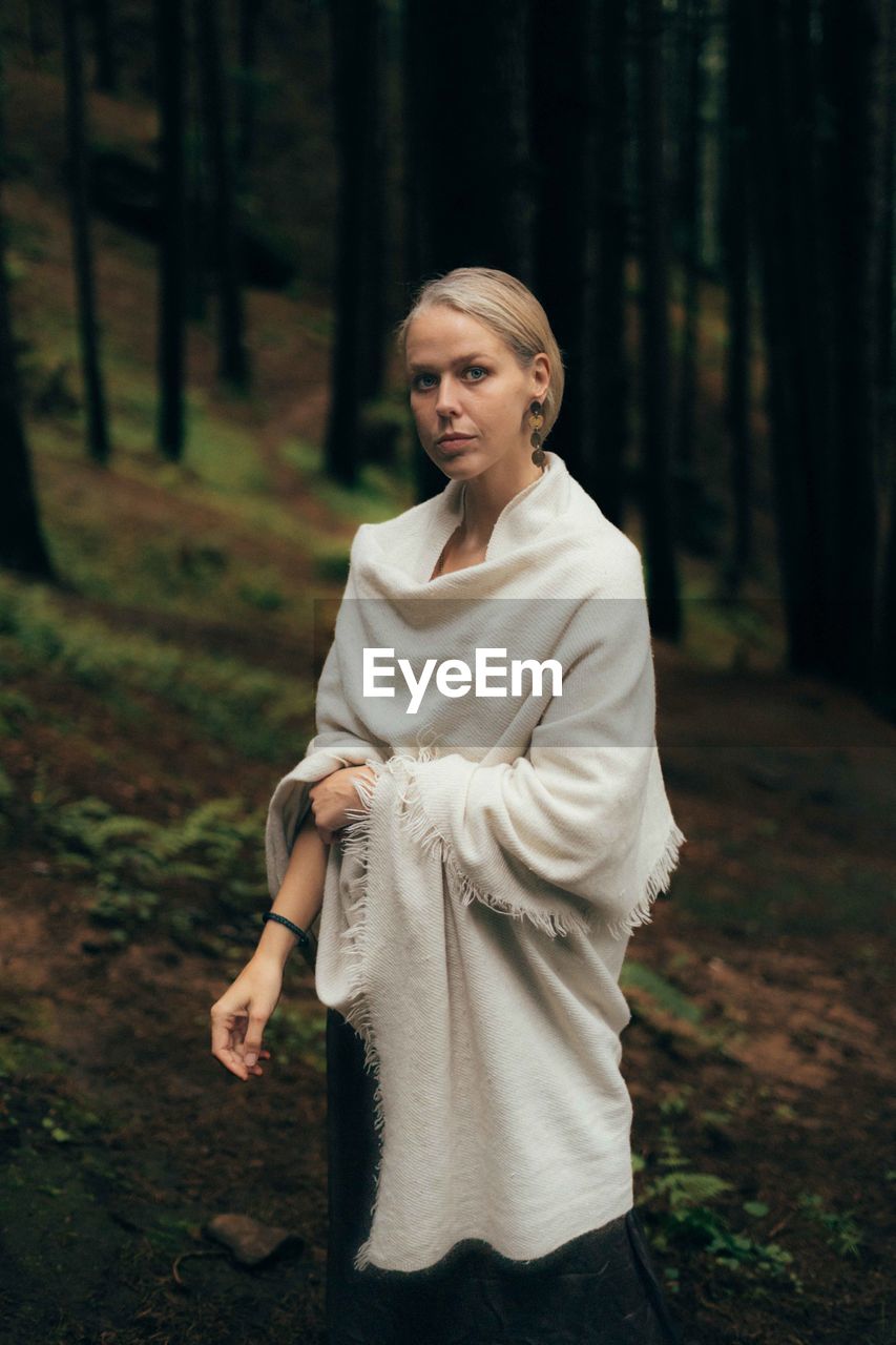 Portrait of young woman standing in forest